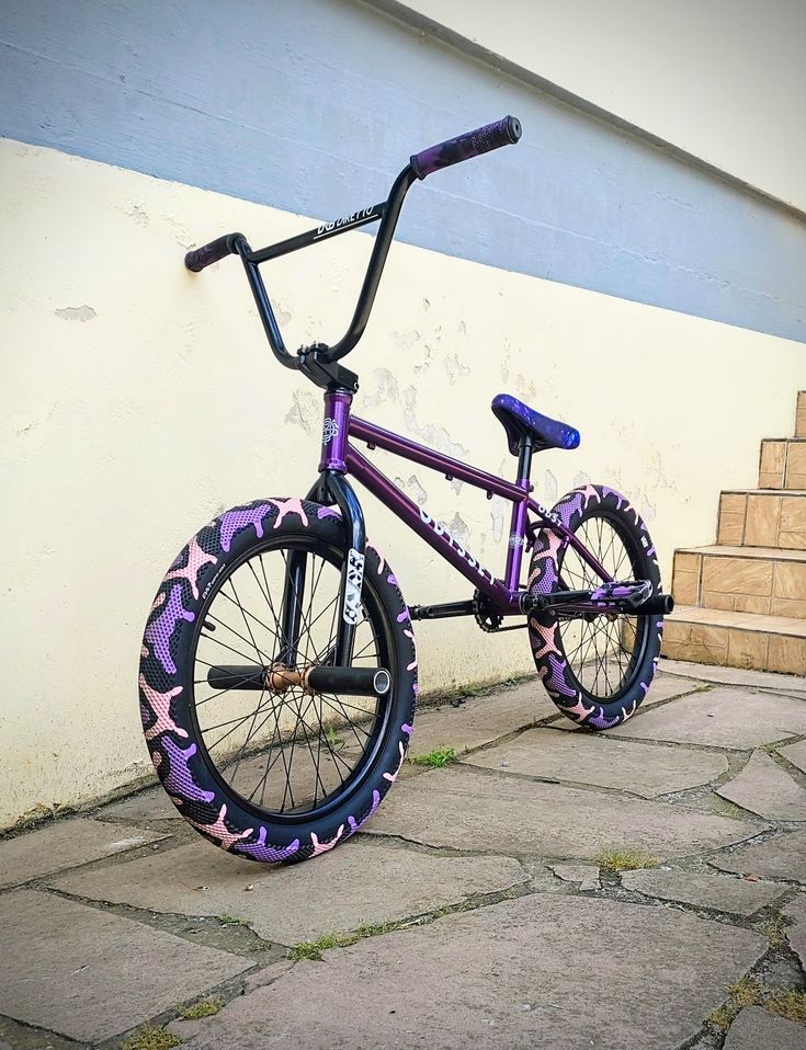 a purple and black bike parked on the side of a building next to some steps