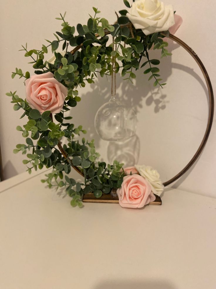 some pink and white flowers are in a glass vase on a table with greenery