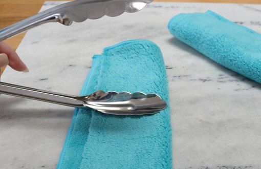 a person is using a spoon to cut up some blue towels on a counter top