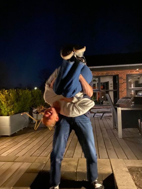 a man holding a baby in his arms while standing on a wooden deck at night