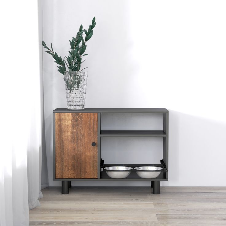 a wooden cabinet with two bowls on it and a plant in the corner next to it