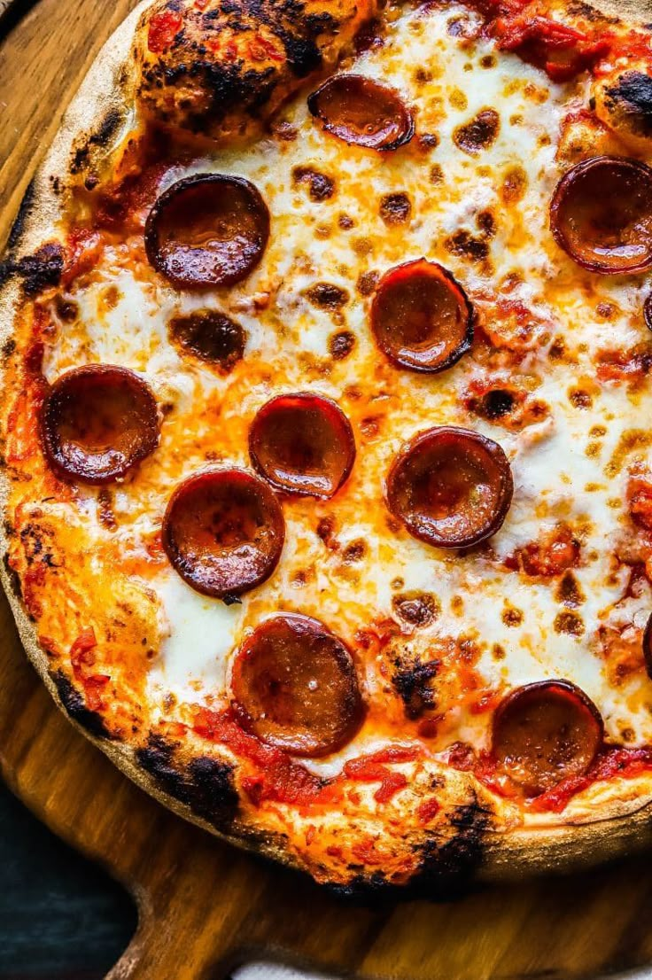 a pizza with pepperoni and cheese on a wooden board