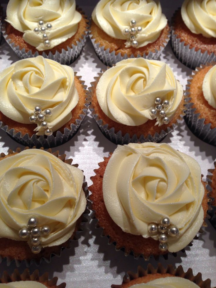 there are many cupcakes with white frosting on the top one is decorated with pearls