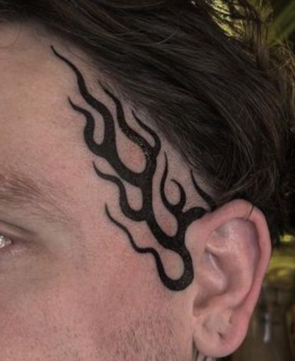 a man's face with a tattoo on his forehead and behind the head is a plant