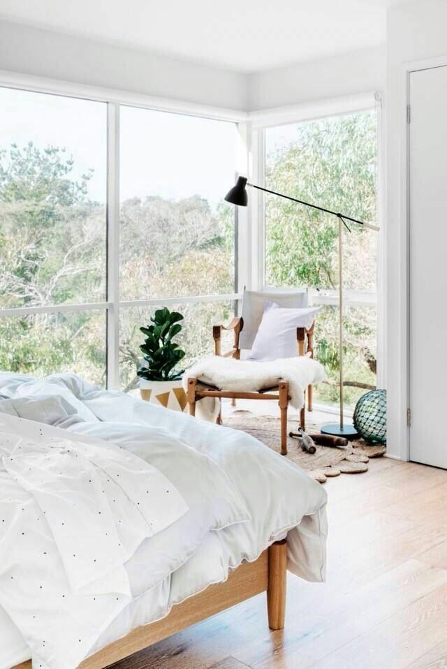 a bed sitting in a bedroom next to a window covered in white sheets and pillows