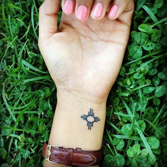 a woman's hand with a small tattoo on it, in the middle of some grass