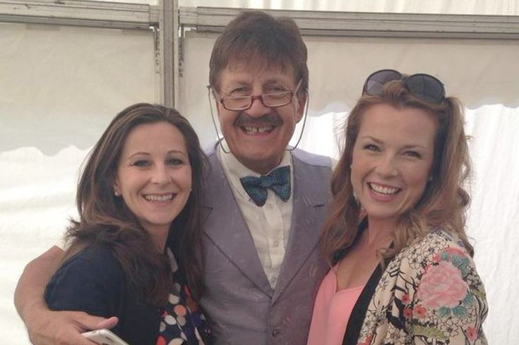 two women and a man are posing for a photo in front of a white tent