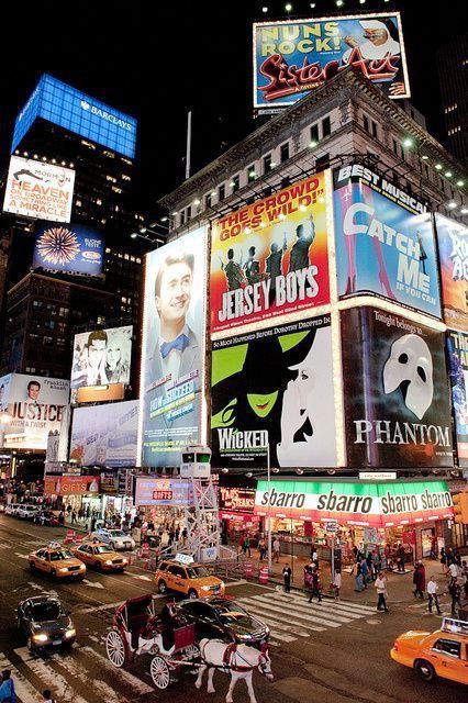 a busy city street at night with lots of billboards on the side of buildings