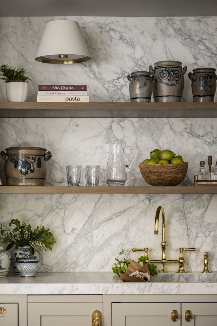 a kitchen with white marble counter tops and gold faucets on wooden shelves above the sink