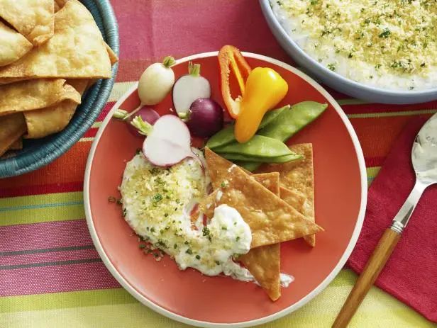 two plates of food on a table with utensils and spoons next to them