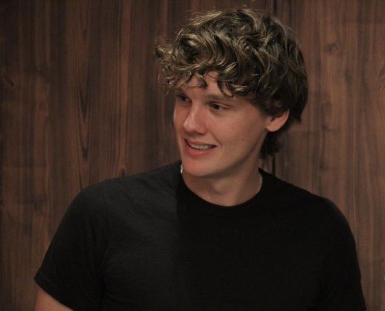 a young man with curly hair is smiling