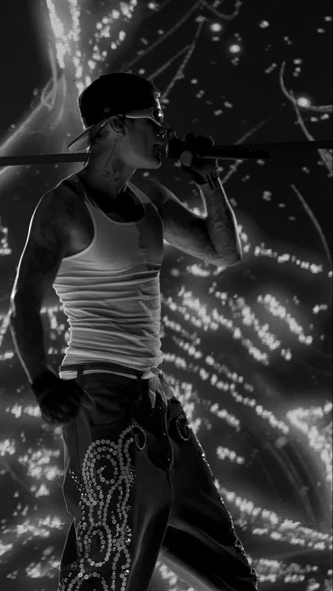 a man standing on top of a stage with a microphone in his hand and lights behind him