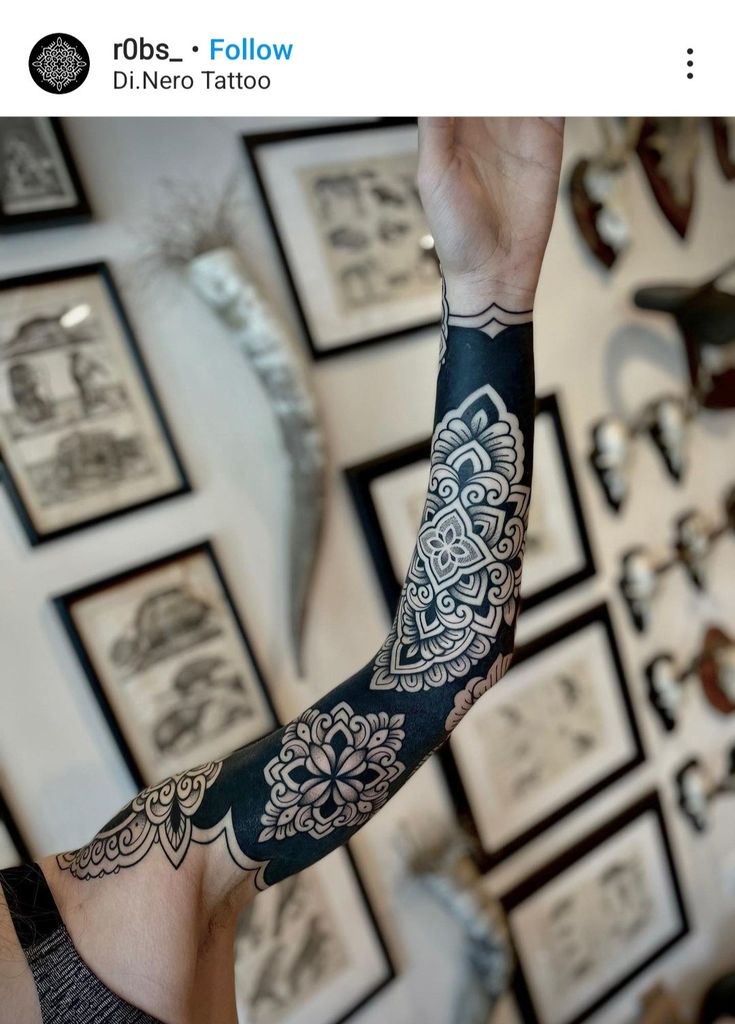 a person with a tattoo on their arm and arms in front of a wall full of pictures