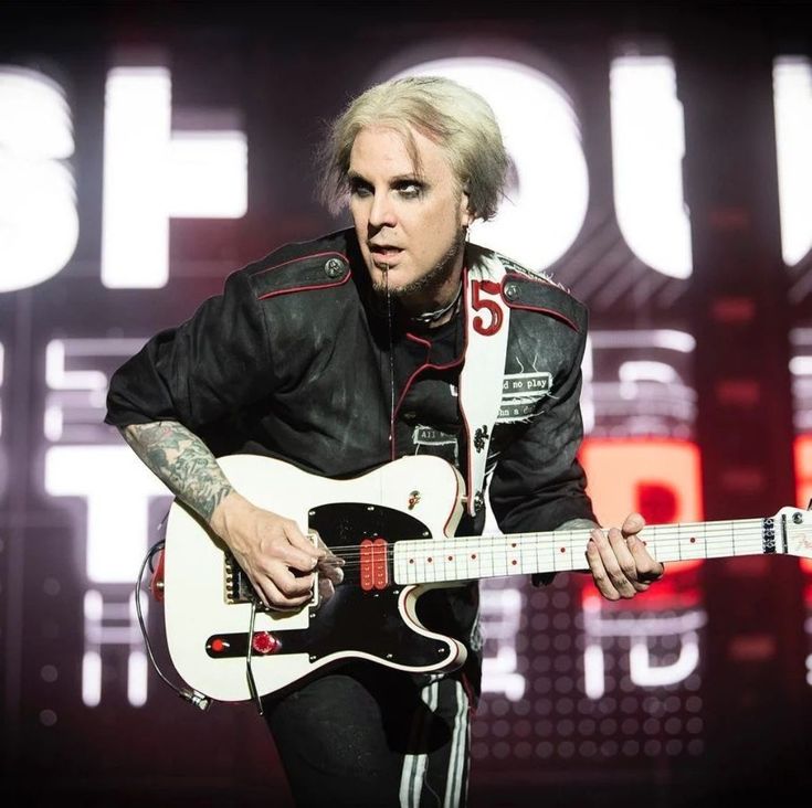 a man with white hair playing an electric guitar