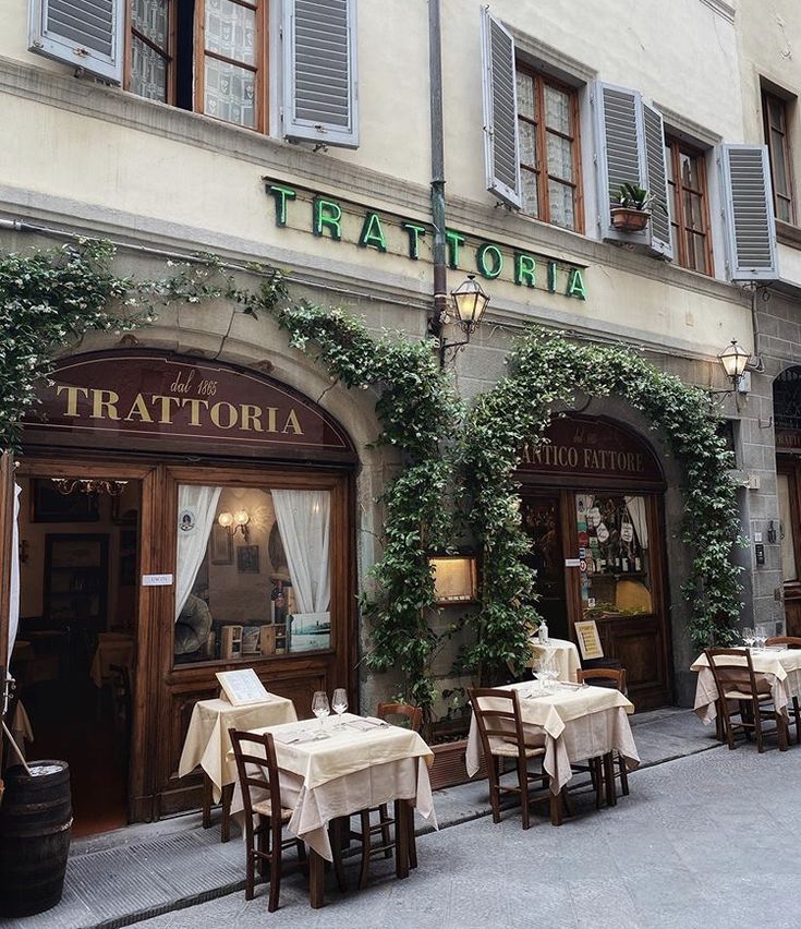 the outside of a restaurant with tables and chairs in front of it, covered by ivy