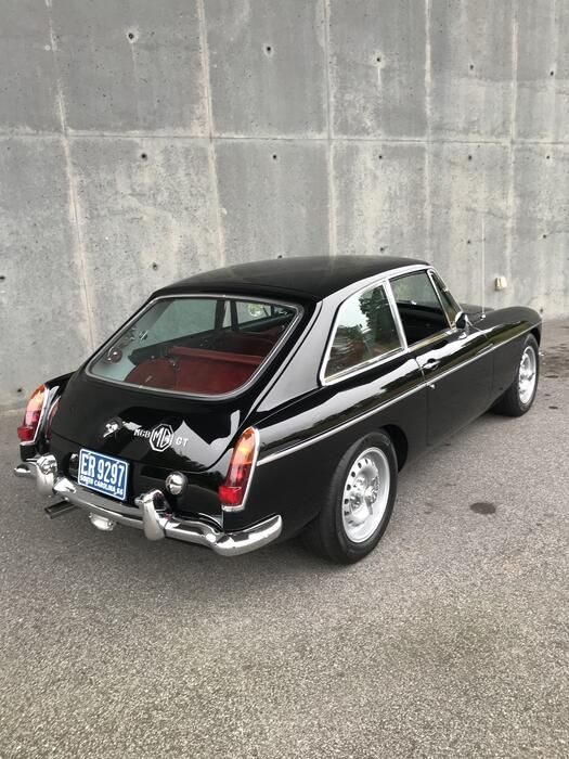 an old black car parked in front of a concrete wall