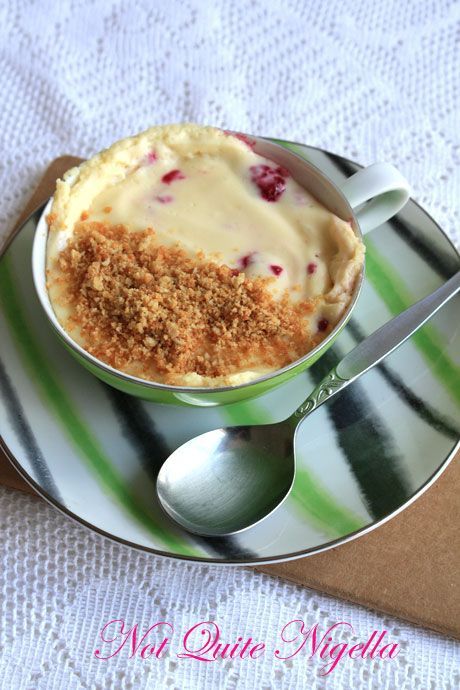 a dessert dish with crumbs and cream on a striped plate next to a spoon