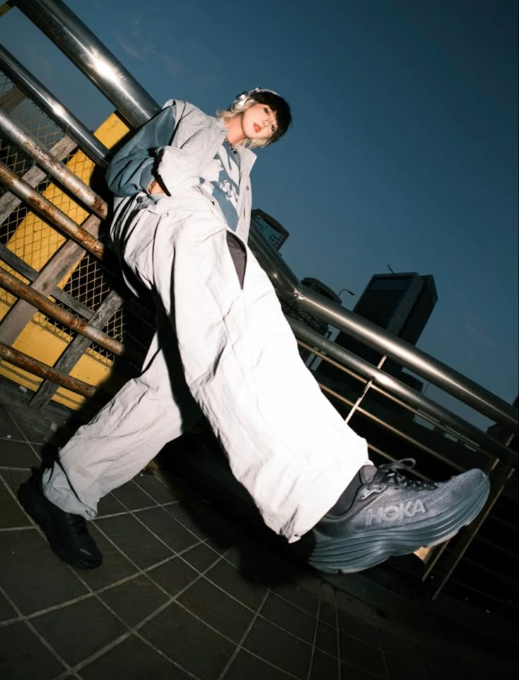 a man is leaning against a fence with his leg up in the air while wearing white pants