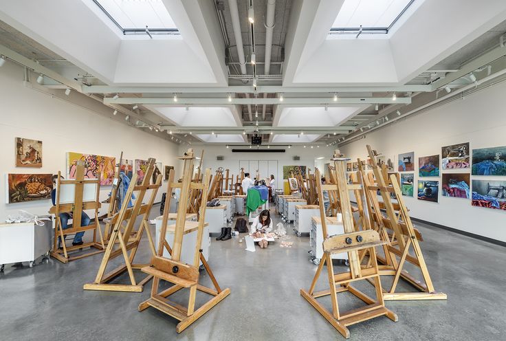 an art gallery filled with lots of wooden easels and paintings on display in front of people