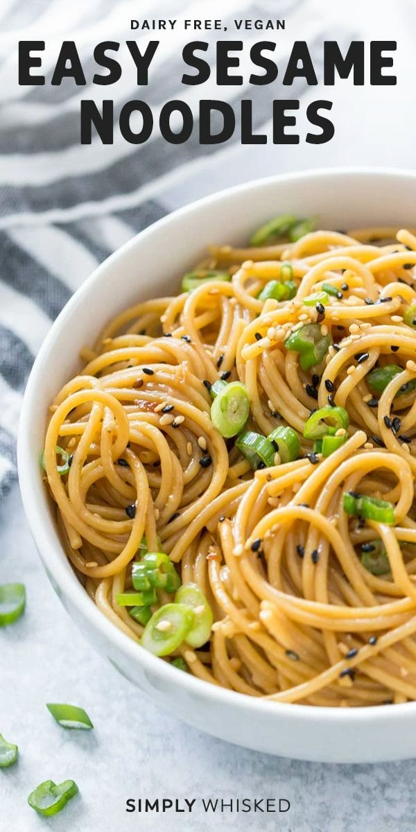 a white bowl filled with noodles and peas on top of a striped cloth next to green onions