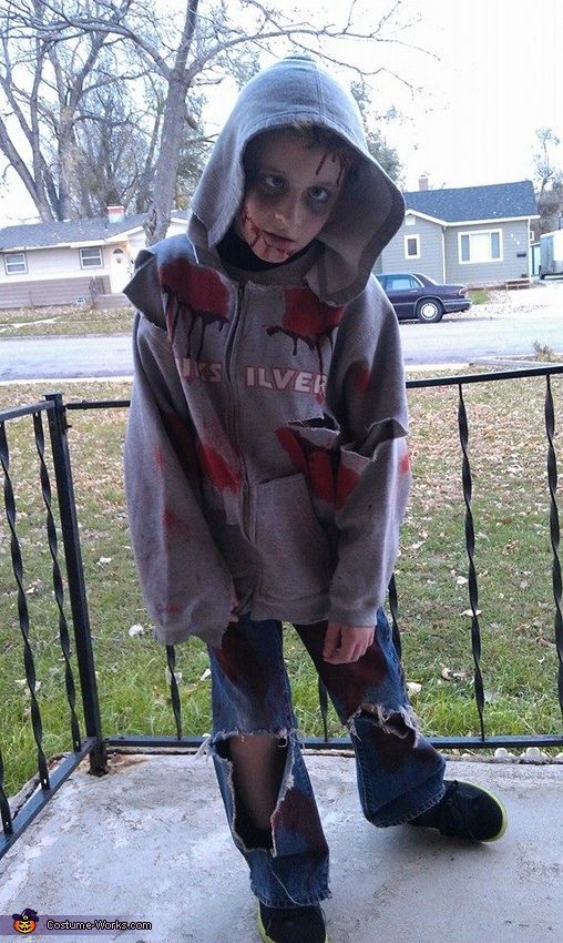 a young child dressed as a zombie standing on a porch with his hands in his pockets