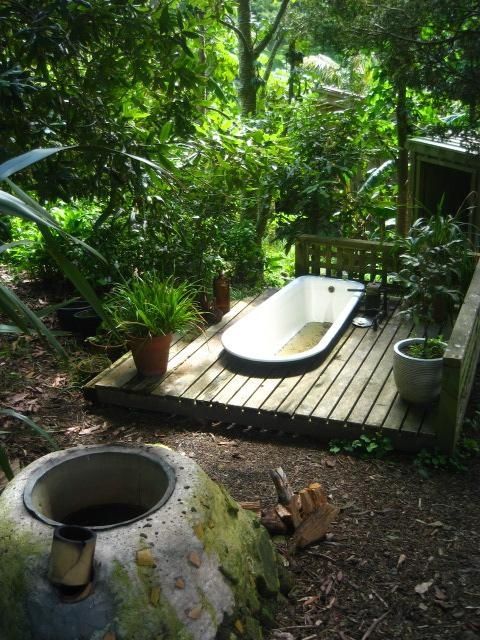 a bathtub sitting on top of a wooden platform in the middle of a forest