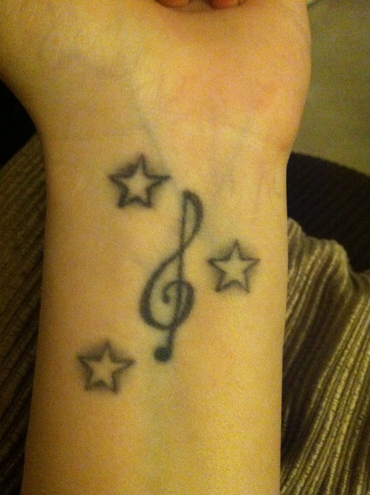 a woman's wrist with a musical note and stars tattoo on her left arm