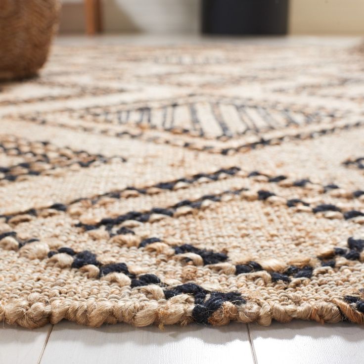 a close up of a rug on the floor with a chair in the back ground