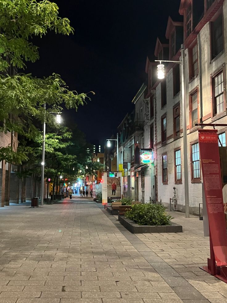 an empty city street at night with people walking on the sidewalk and buildings in the background