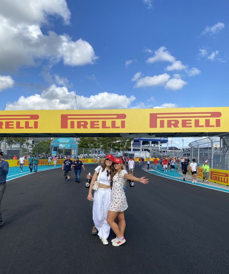 two women standing in the middle of a race track under a yellow sign that says hell irell