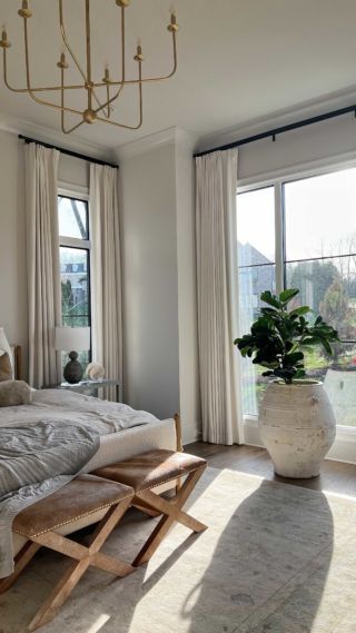 a bedroom with a large bed sitting next to two windows and a chandelier hanging from the ceiling