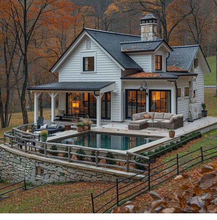 a white house with a pool in front of it and lots of trees around it