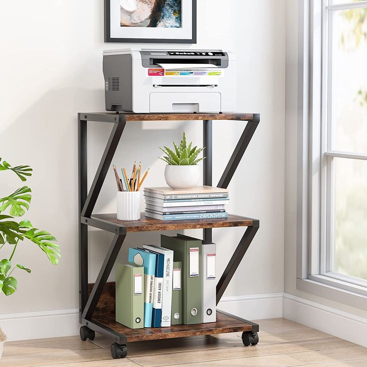 a printer is sitting on top of a book shelf next to a potted plant