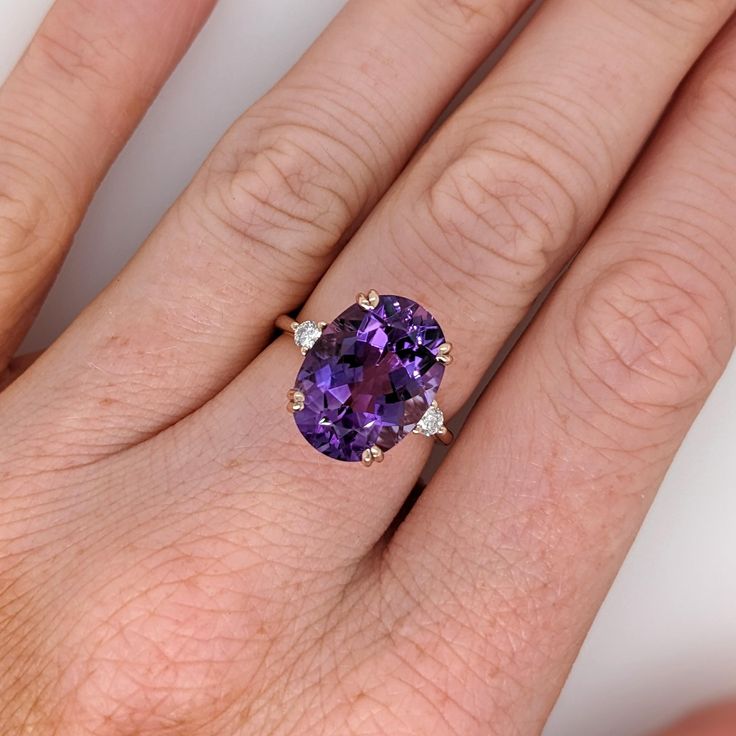 a woman's hand with a ring on it and a purple stone in the middle