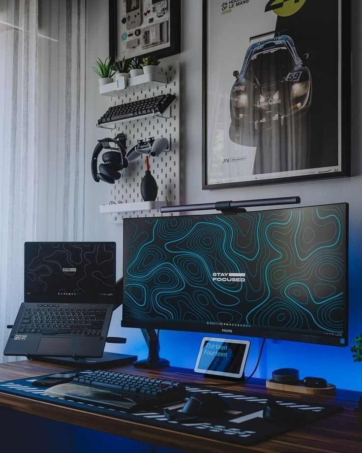 two laptops sitting on top of a wooden desk in front of a computer monitor