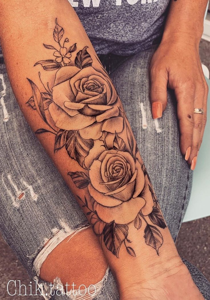 a woman's arm with roses and leaves tattooed on the side of her leg