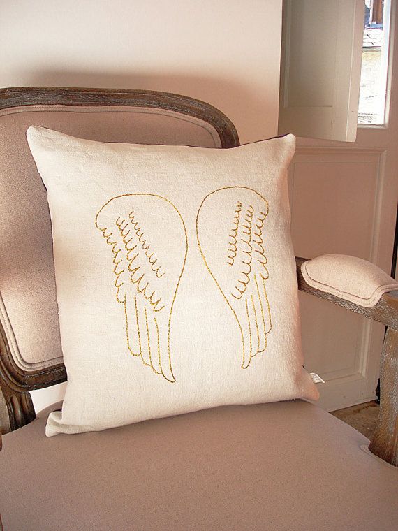 a white pillow sitting on top of a chair next to a wooden armoire with two angel wings drawn on it