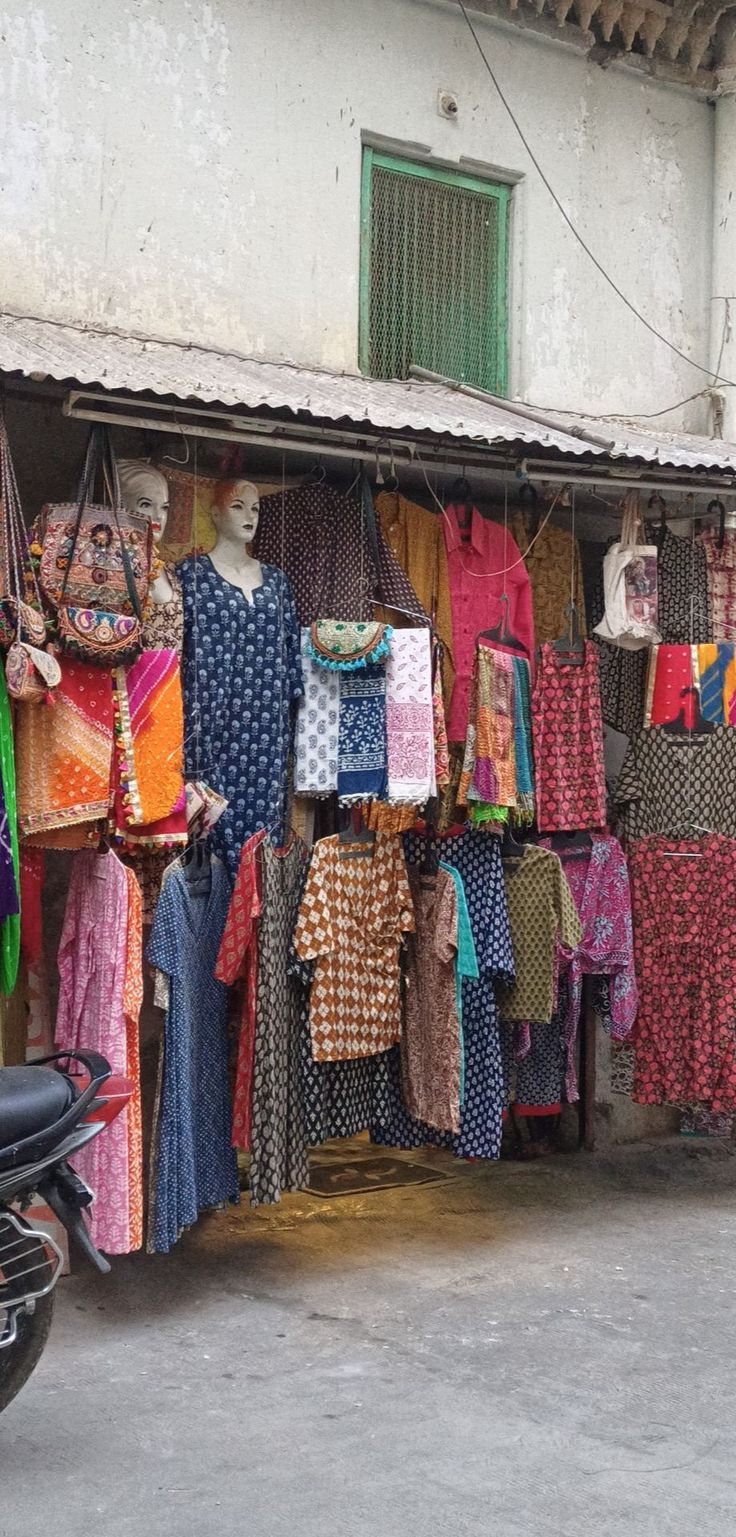 clothes are hanging up in front of a building with a motorcycle parked next to it