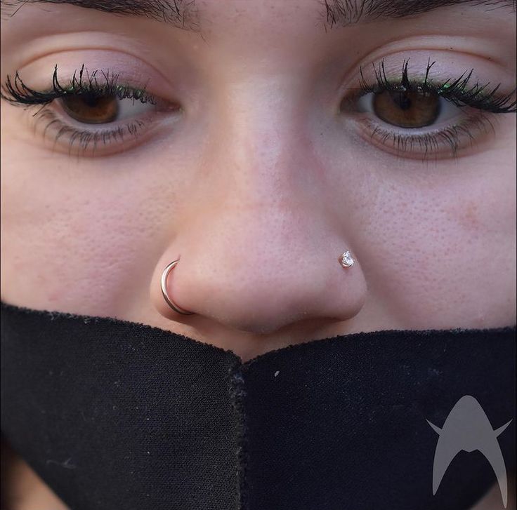 a close up of a person with fake eyelashes and nose ring on her nose, wearing a black scarf around her neck