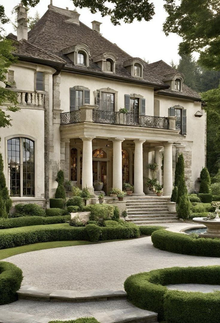 a large white house with lots of windows and bushes in front of the entrance to it