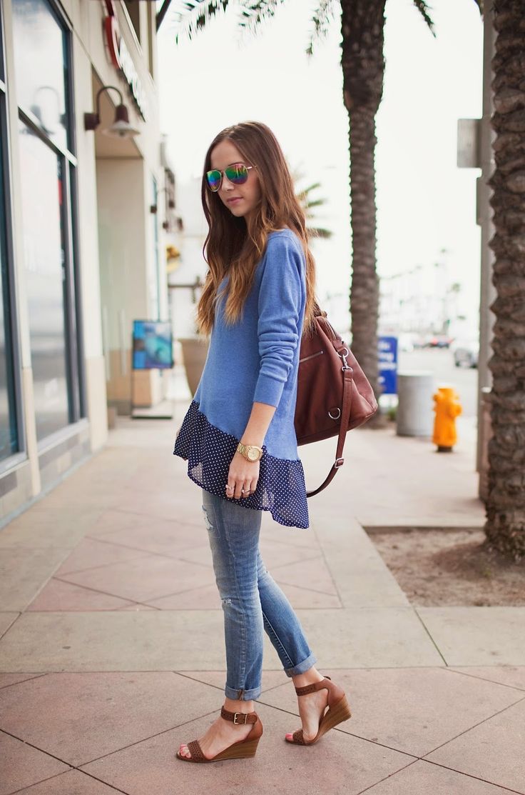 a woman is walking down the sidewalk with her hand in her pocket and wearing sunglasses