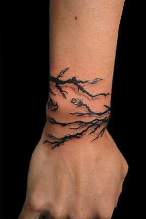 a wrist tattoo with branches on it and the words,'let him know what he is