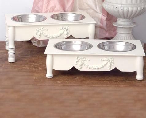 two white dog bowls are sitting next to each other in front of a pink curtain