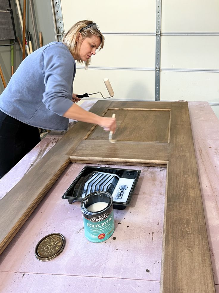 a woman painting a wooden table with white paint