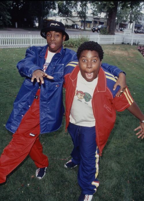 two young men standing next to each other on top of a grass covered park area