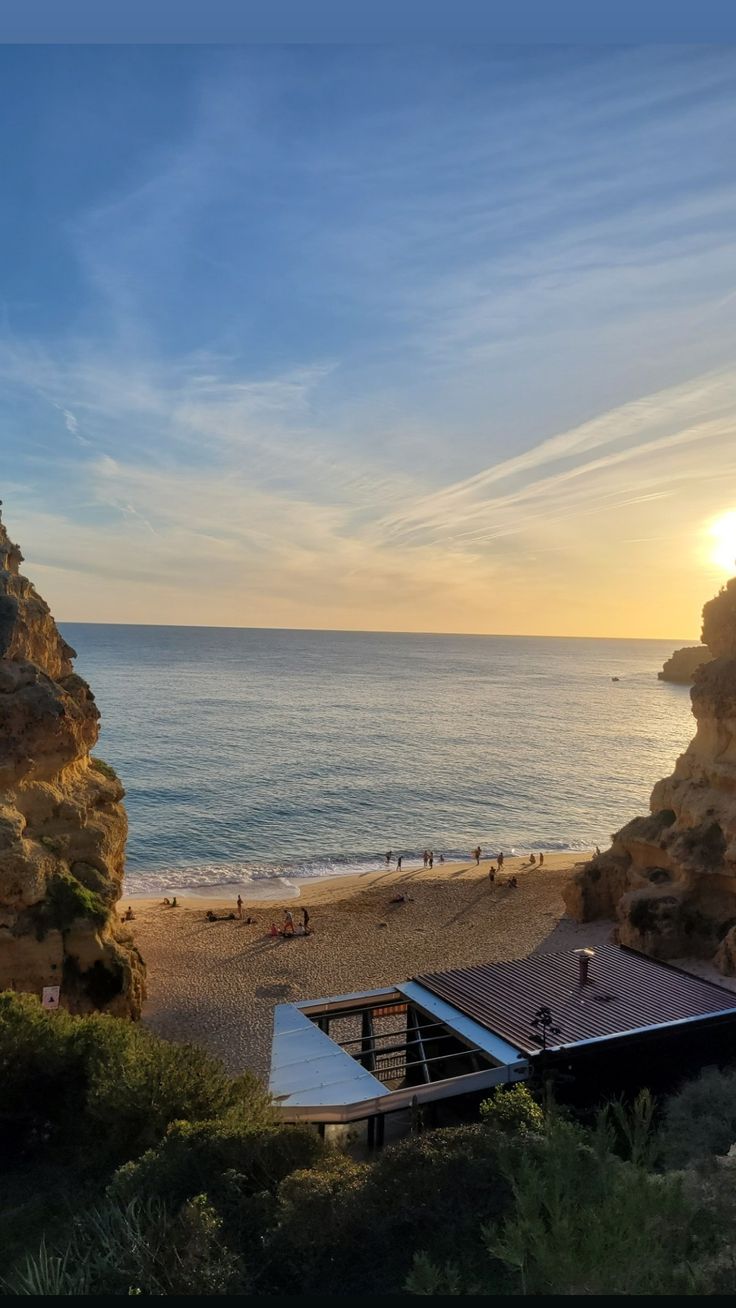 the sun is setting over the beach with people on it