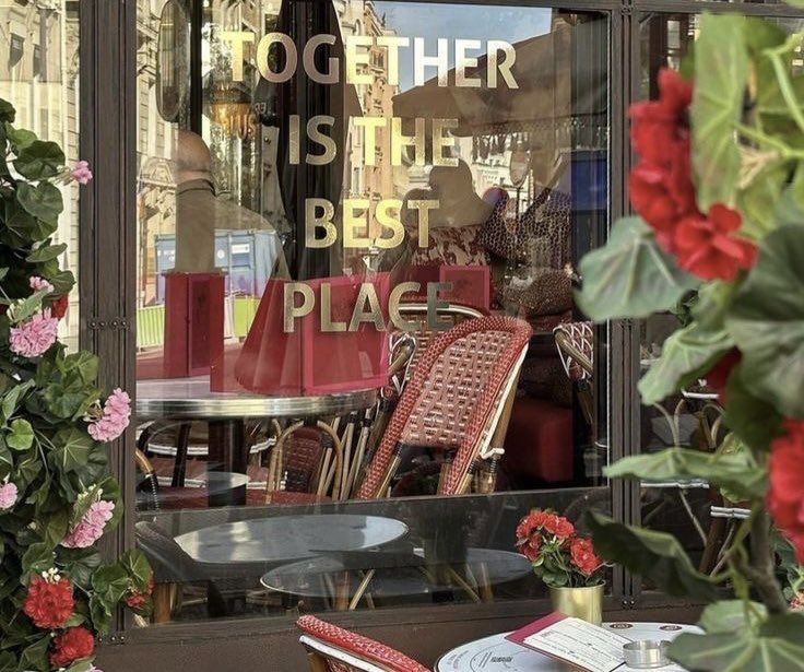 there are many chairs and tables in the store front window with red flowers on it