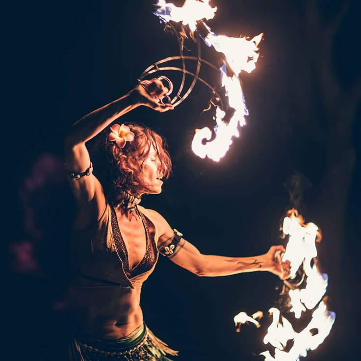 a woman is performing with fire and hoop