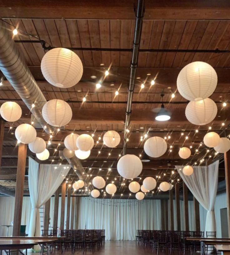 a large room filled with lots of white paper lanterns