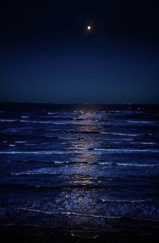 the moon is shining over the ocean at night